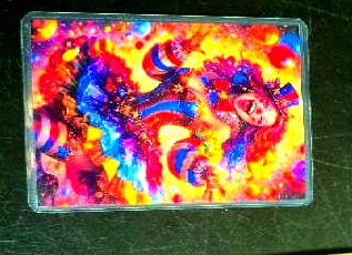 The clown card lying on the dark table, an explosion of carnival colour