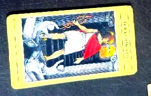 The Judgment tarot card with its bright yellow border, lying on the dark table