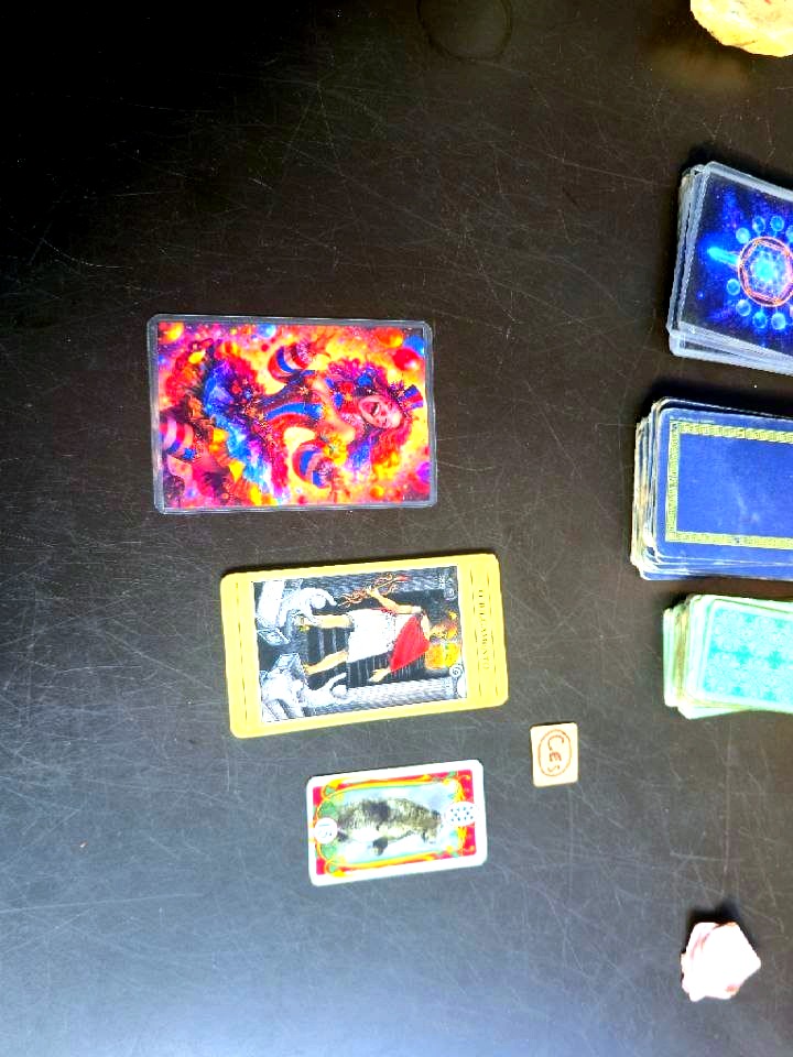 The full spread on the dark table: the clown, Judgment and the fish laid out beside the stacked decks